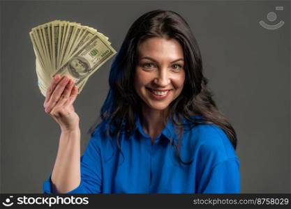 Satisfied happy excited adult woman showing money - U.S. currency dollars banknotes on grey wall. Symbol of success, gain, victory. Satisfied happy excited adult woman showing money - U.S. currency dollars banknotes on grey wall. Symbol of success, gain, victory.