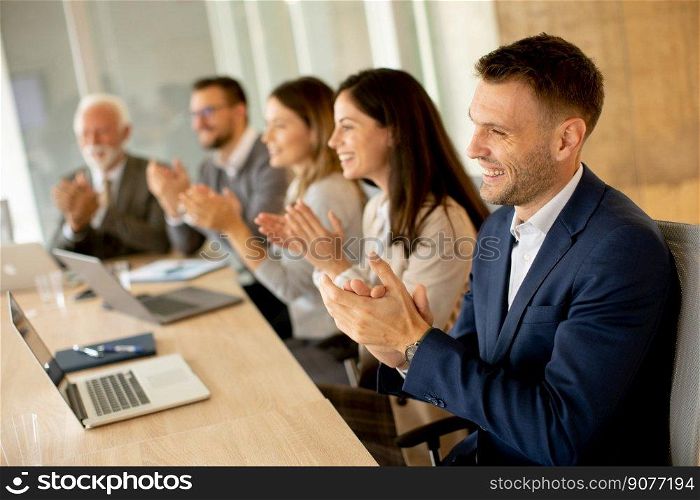 Satisfied proud business team clapping hands while sitting in row at office