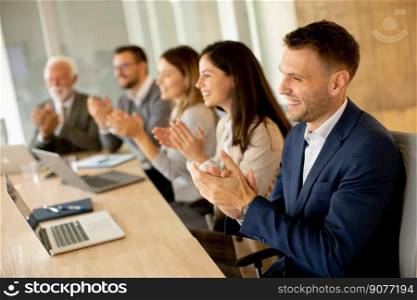Satisfied proud business team clapping hands while sitting in row at office