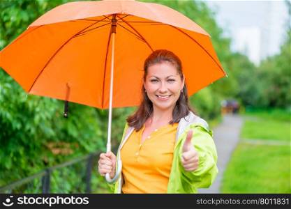 Satisfied woman with umbrella on the walk in the park