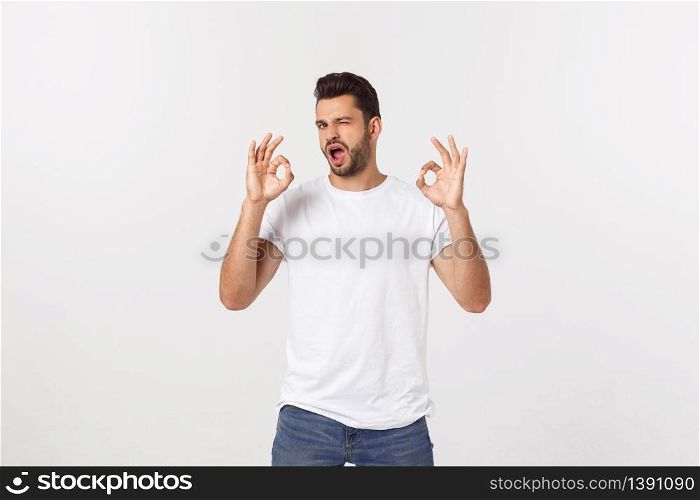 Satisfied young man showing okay sign isolated on white background. Satisfied young man showing okay sign isolated on white background.