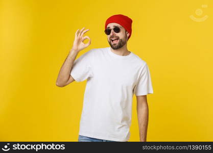 Satisfied young man showing okay sign isolated on yellow background. Satisfied young man showing okay sign isolated on yellow background.