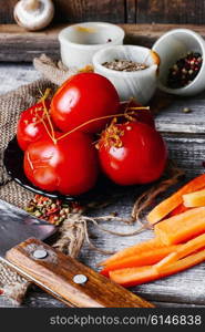 Saucer of pickled tomatoes on wooden background in rustic style. Appetizer with marinated tomatoes