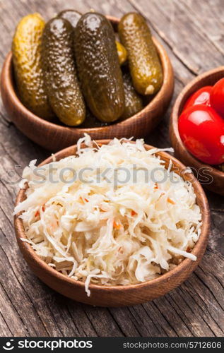 Sauerkraut and pickled cucumbers and tomatoes in wooden bowls