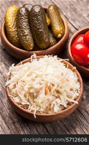 Sauerkraut and pickled cucumbers and tomatoes in wooden bowls