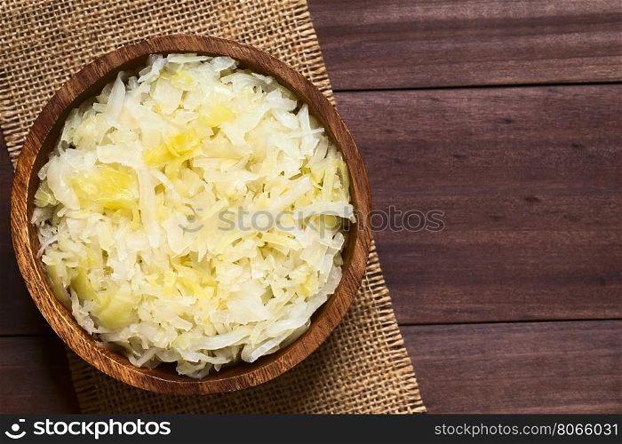 Sauerkraut in wooden bowl, photographed overhead on dark wood with natural light (Selective Focus, Focus on the top of the sauerkraut)