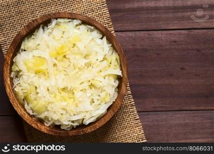 Sauerkraut in wooden bowl, photographed overhead on dark wood with natural light (Selective Focus, Focus on the top of the sauerkraut)