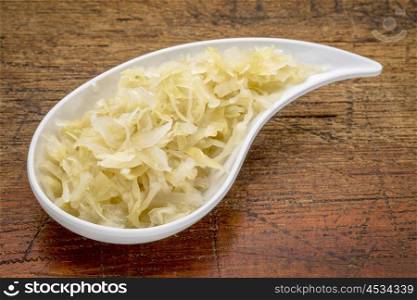 sauerkraut side dish - a white teardrop shaped bowl against rustic wood