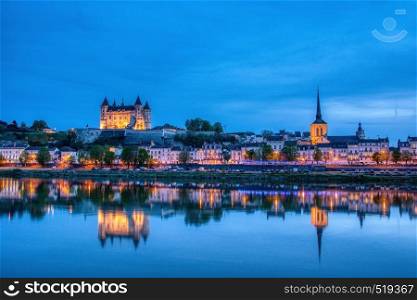 Saumur, France - April 18, 2019: Panorama of Saumur at night with the medieval castle and the old town with Saint-Pierre church, Pays de la Loire, France.