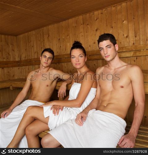 Sauna spa therapy beautiful young people group in warm wood room white towel