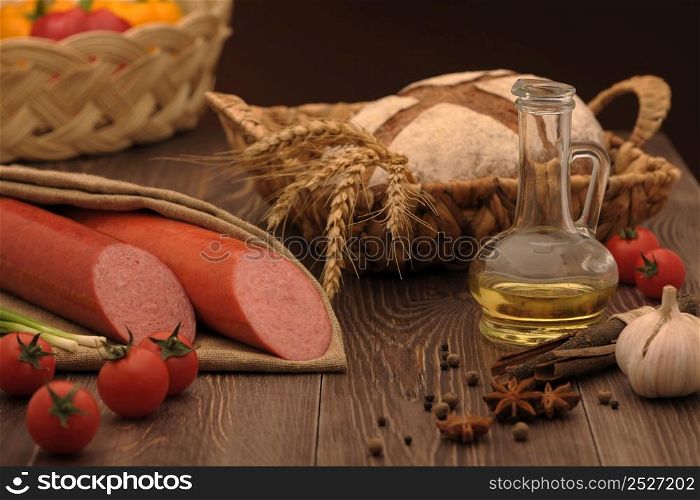 sausage and bread in a wicker basket and vegetables and garlic on a table. sausage and bread on the table