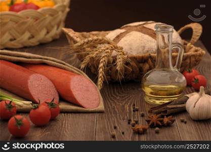 sausage and bread in a wicker basket and vegetables and garlic on a table. sausage and bread on the table