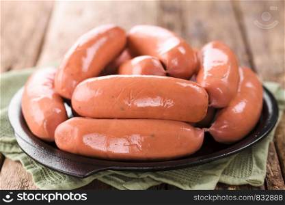 Sausage or bratwurst on cast-iron plate (Selective Focus, Focus on the first two sausages). Sausage or Bratwurst
