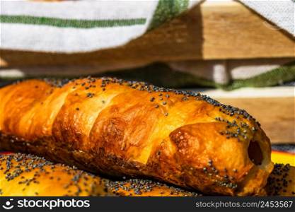 Sausages baked in dough sprinkled with salt and poppy seeds in a rustic composition. Sausages rolls, delicious homemade pastries.. Sausages baked in dough sprinkled with salt and poppy seeds in a rustic composition. Sausages rolls, delicious homemade pastries.