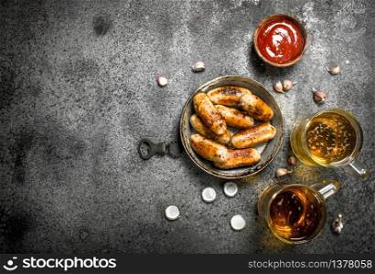Sausages in a frying pan with a cold beer. On a rustic background.. Sausages in a frying pan with a cold beer.