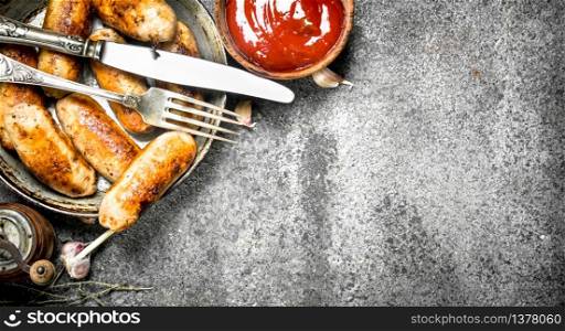Sausages in a frying pan with tomato sauce. On a rustic background.. Sausages in a frying pan with tomato sauce.