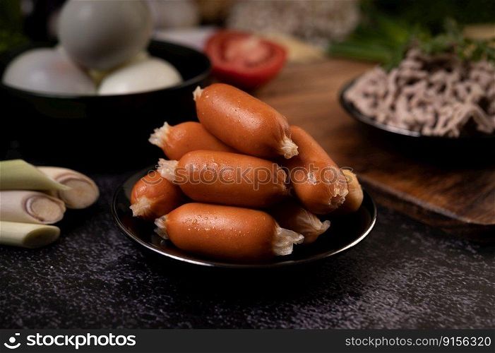 Sausages on a black plate that are placed on the cement floor. Selective focus.