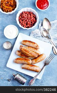 sausages on white plate, fried sausages with sauce