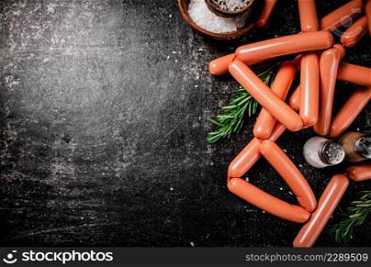 Sausages with spices and rosemary on the table. On a black background. High quality photo. Sausages with spices and rosemary on the table.