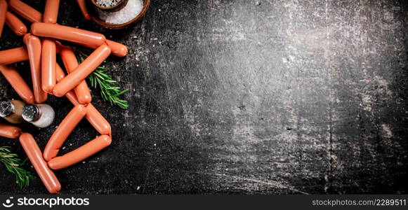 Sausages with spices and rosemary on the table. On a black background. High quality photo. Sausages with spices and rosemary on the table.