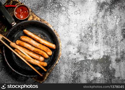 Sausages with tomato sauce on the board. On a rustic background.. Sausages with tomato sauce on the board.