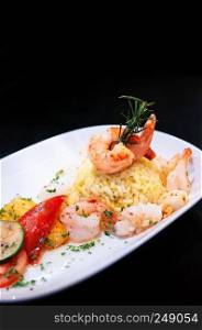 Saute shrimps, scallop, squid with pepper chilli with Mediterranian roast vegetable and saffron rice on white plate dark background