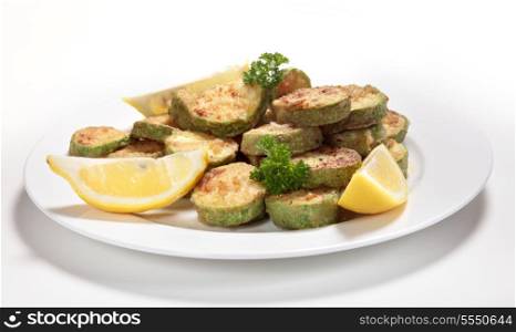 Sauteed courgette (zucchini) slices served with lemon wedges and garnished with parsley. The the courgettes are sliced, tossed in flour and fried in butter or olive oil and then seasoned.