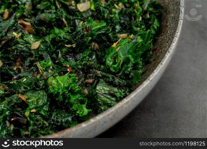 sauteed kale with onion in a pan with olive oil, healthy cooking concept. sauteed kale plant