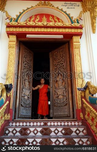 SAVANNAKHET, LAOS - CIRCA FEBRUARY 2017 Monk opens the door in the temple in Wat Sainyaphum