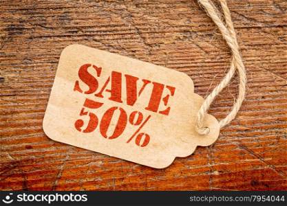save 50 percent sign a paper price tag against rustic red painted barn wood - shopping concept