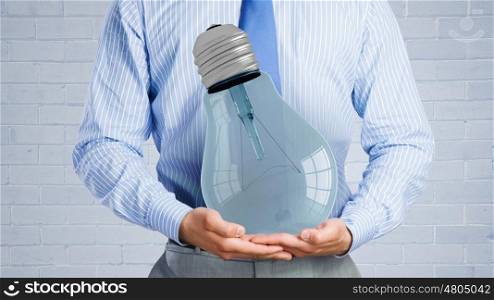 Save energy. Close up of businessman hands holding glass light bulb