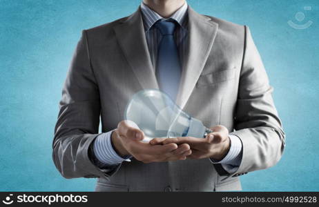 Save energy. Close up of businessman hands holding glass light bulb