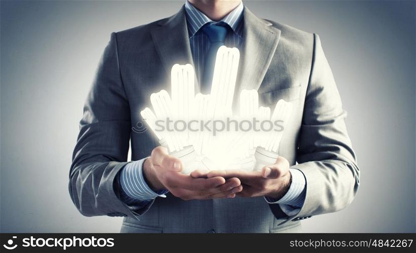 Save energy. Close up of businessman hands holding glass light bulbs