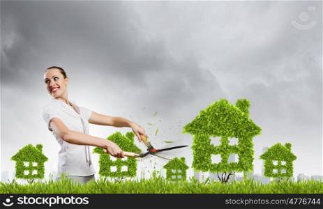 Save home. Young businesswoman cutting plant shaped like house. Ecology concept