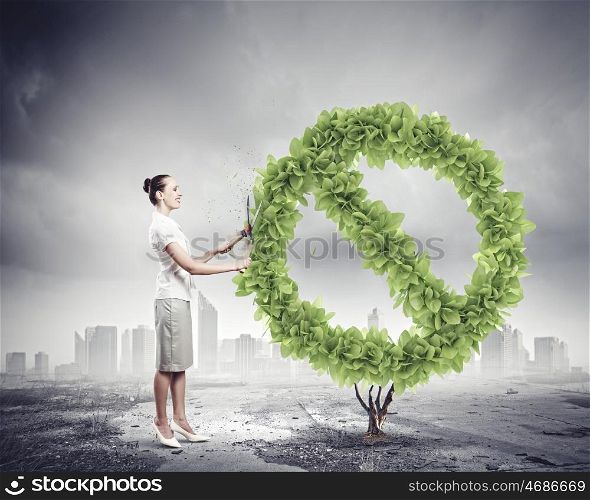 Save home. Young businesswoman cutting plant shaped like prohibition sign. Ecology concept