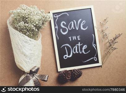 Save the date written on blackboard with bouquet of flower, retro filter effect