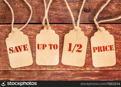 save up to half price banner - sign on paper price tags against a rustic barn wood