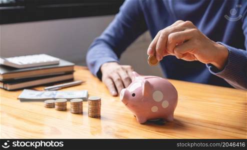 saving concept the male picking his coin to drop it into a pink piggy bank as his money saving up for this month.