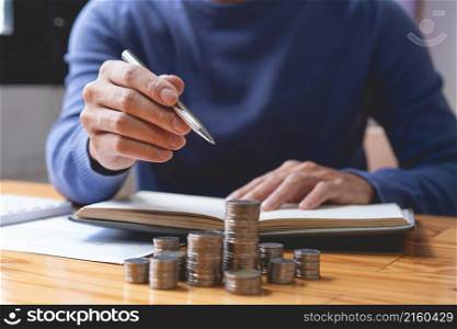 saving concept the male who is holding a silver pencil counting his money and doing revenue account on his notebook.