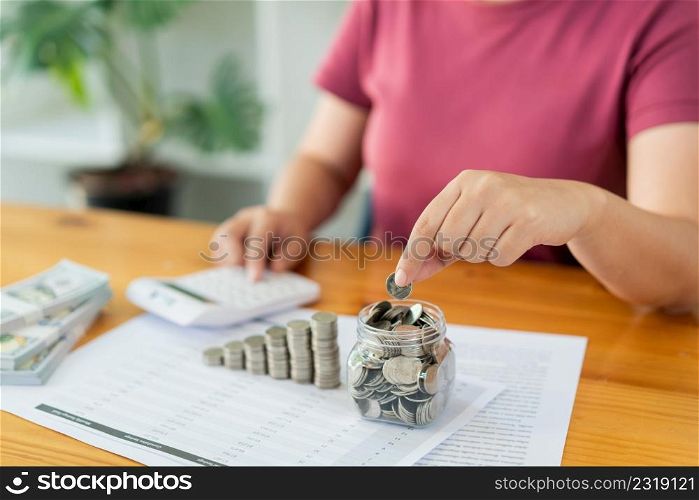 Saving concept the woman piling her coins and counting the money by using the calculator.