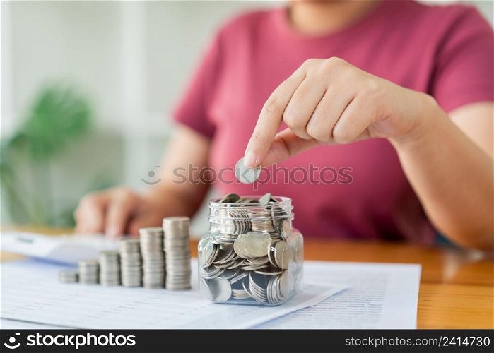 Saving concept the woman piling her coins and counting the money by using the calculator.
