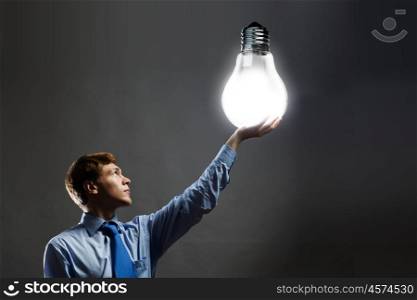 Saving energy. Young man holding light bulb in hand