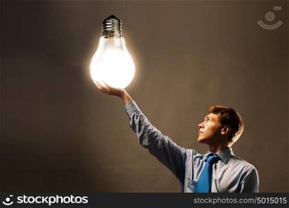 Saving energy. Young man holding light bulb in hand