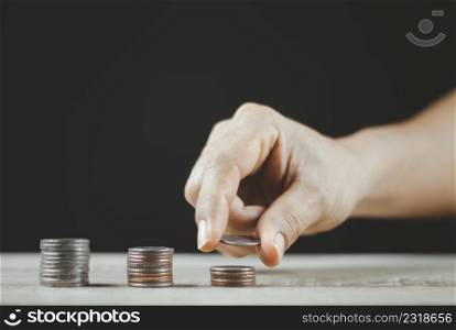 Saving money concept. Male hand putting money coin stack for the future growing business, education and retirement. He felt that saving money made his life safe.