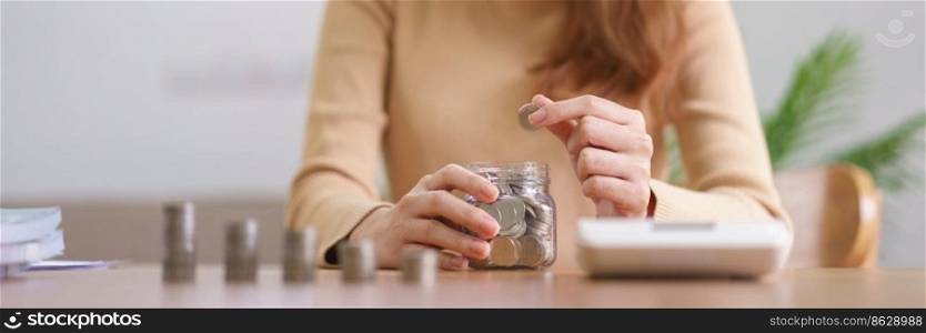Saving money concept, Young Asian woman picking coin put into glass jar for business and future.