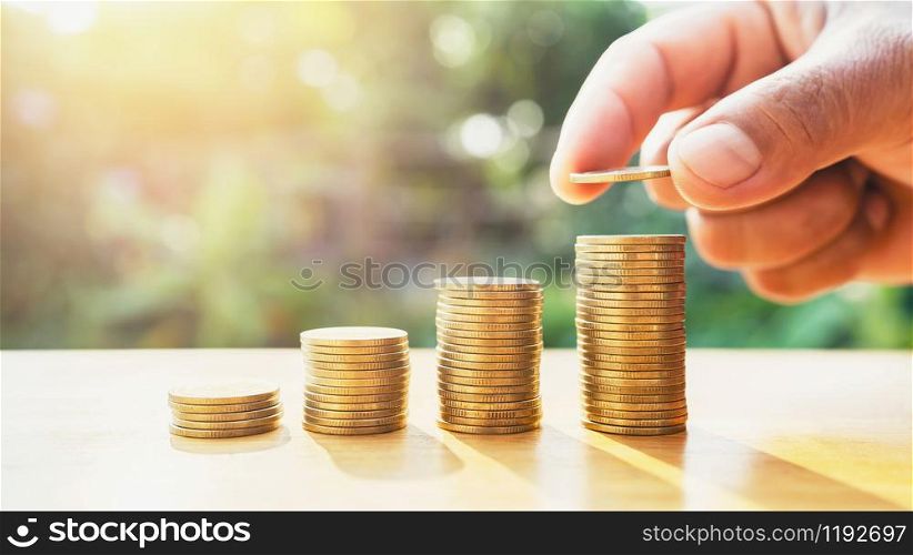 saving money hand putting coins on stack on table with sunshine. concept finance and