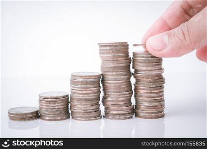saving money, hand putting money coin stack on white background
