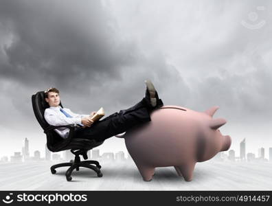 Saving money. Young handsome businessman sitting in chair. Banking concept