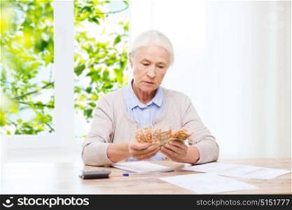 savings, age and people concept - senior woman with calculator and bills counting euro money at home over window and green natural background. senior woman with money and papers at home