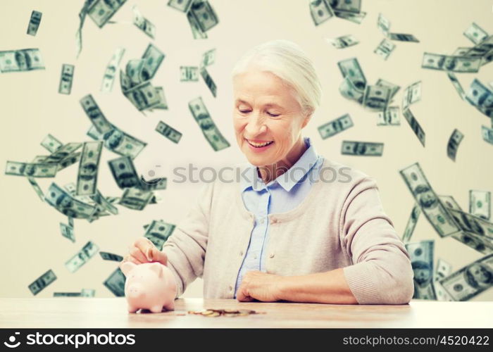 savings, finances, annuity insurance, retirement and people concept - smiling senior woman putting coins into piggy bank over money rain background